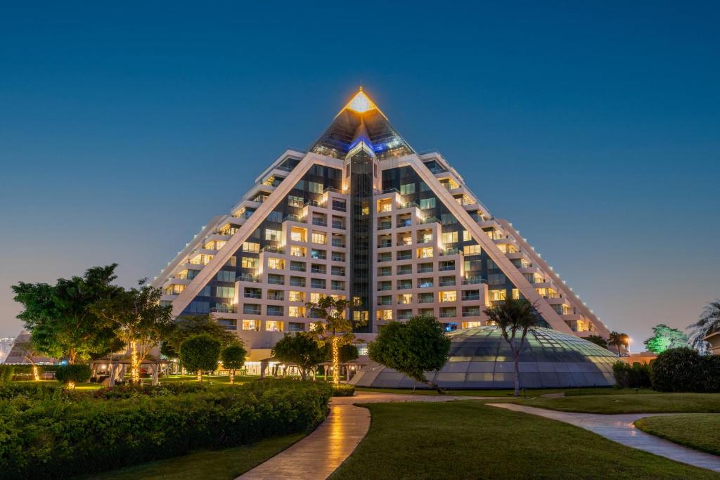 ein hohes Gebäude mit pyramidenförmigem Dach in der Nacht in der Unterkunft Raffles Dubai in Dubai