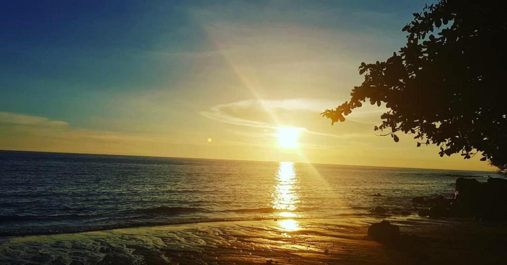 a sunset over the ocean with the sun setting at Jancas Vacation Home Camiguin Couple Room 2 in Catarman