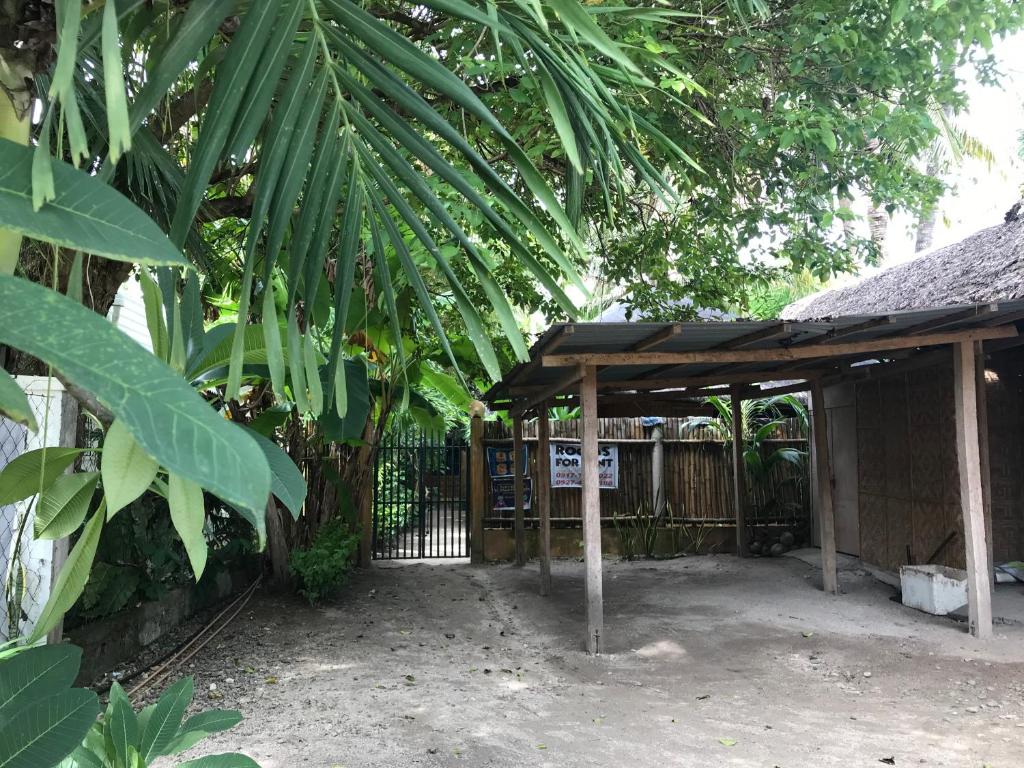 a wooden shelter with a fence and a tree at CafeMare Rooms in Bantayan Island
