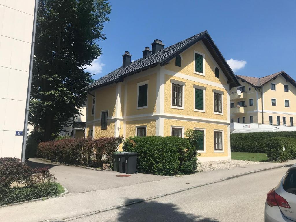una casa amarilla con persianas verdes en una calle en Haus Traundorf en Gmunden