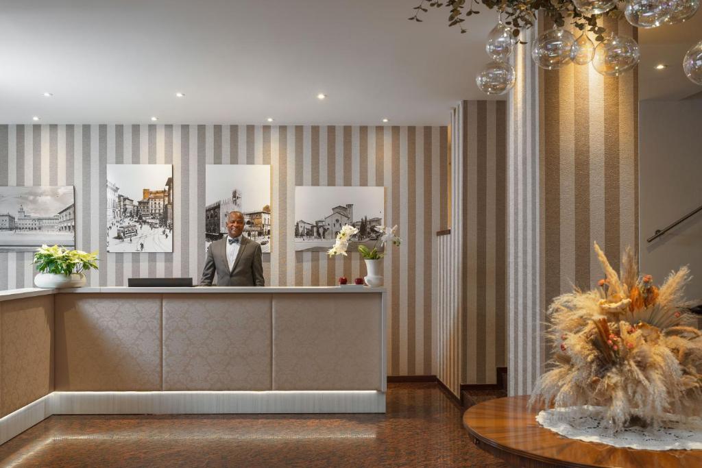Hotel Re Enzo في بولونيا: رجل في بدلة يجلس في مكتب الاستقبال