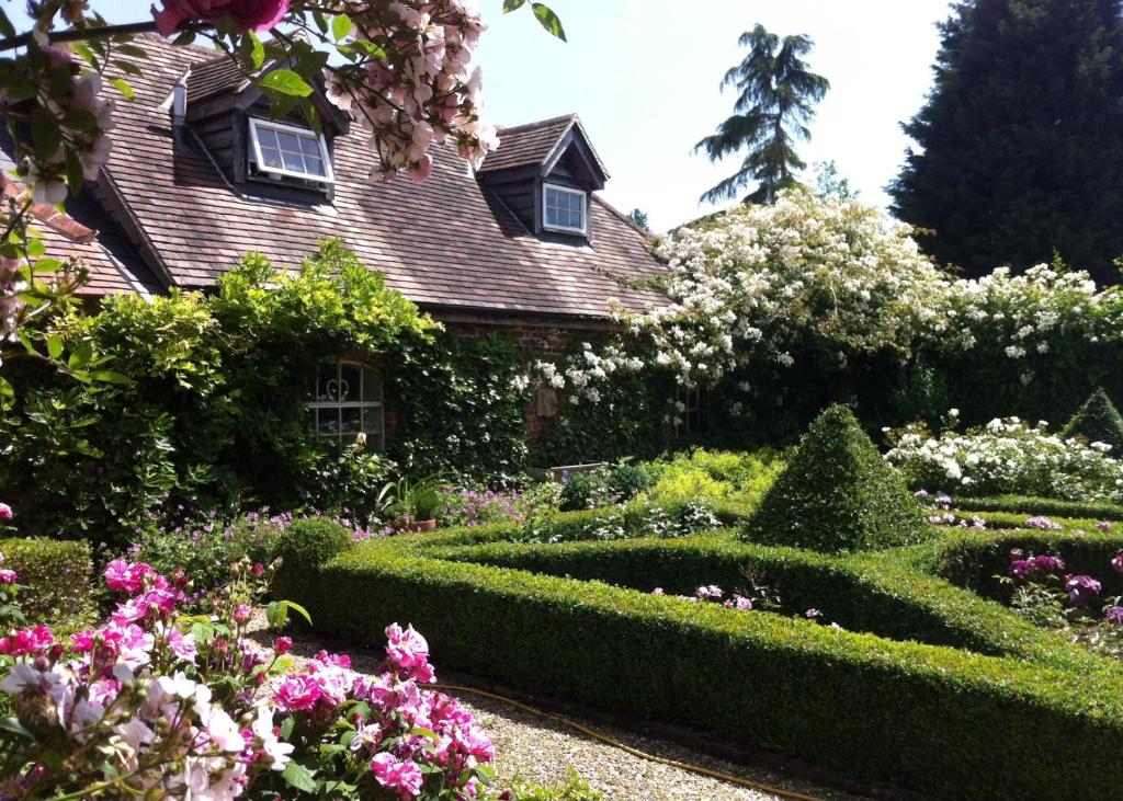 a garden in front of a house with bushes and flowers at The Lodge at Briar house in Long Melford