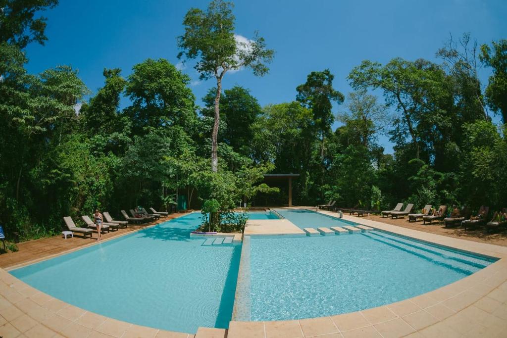 uma grande piscina com espreguiçadeiras e árvores em Hotel Tré Iguazú em Porto Iguaçu
