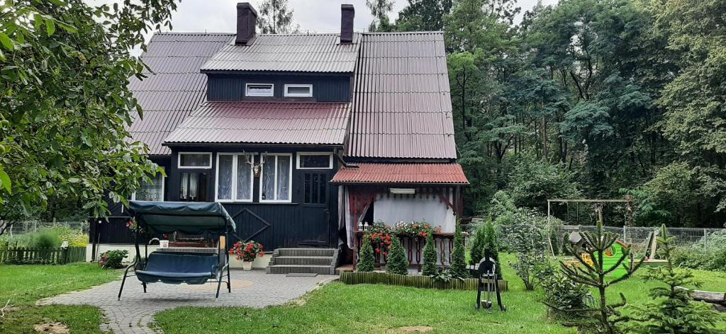 una casa azul con techo rojo y patio en Domek - Leśna Kryjówka, en Promnik