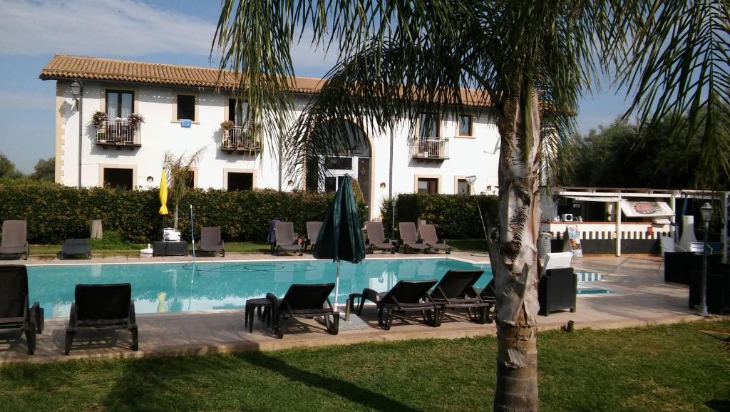 ein Resort mit einem Pool mit Stühlen und einem Gebäude in der Unterkunft Aranceto Hotel Agriturismo in Arenella