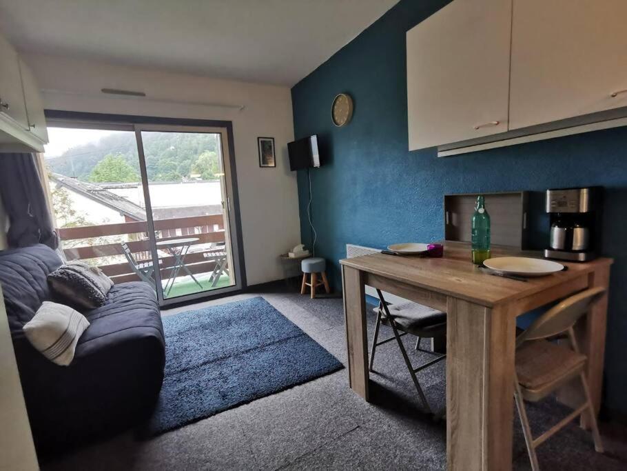 uma sala de estar com um sofá e uma mesa em Joli studio vue sur les montagnes avec balcon em Cauterets