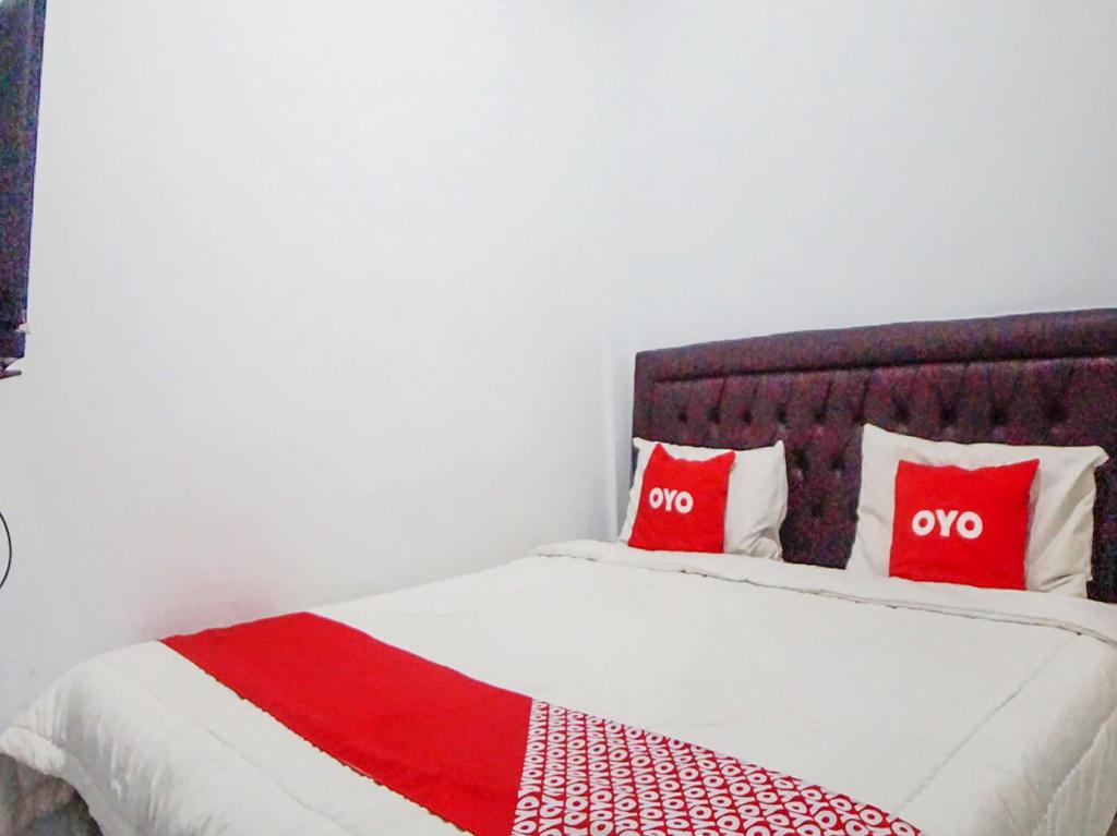 a bed with two red pillows on top of it at SUPER OYO 91627 Wika Wiki Homestay in Medan