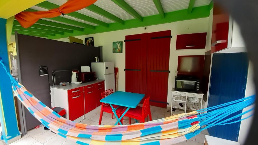 una cocina con armarios rojos y una mesa azul en una habitación en Passion Caraïbes, en Saint-Claude