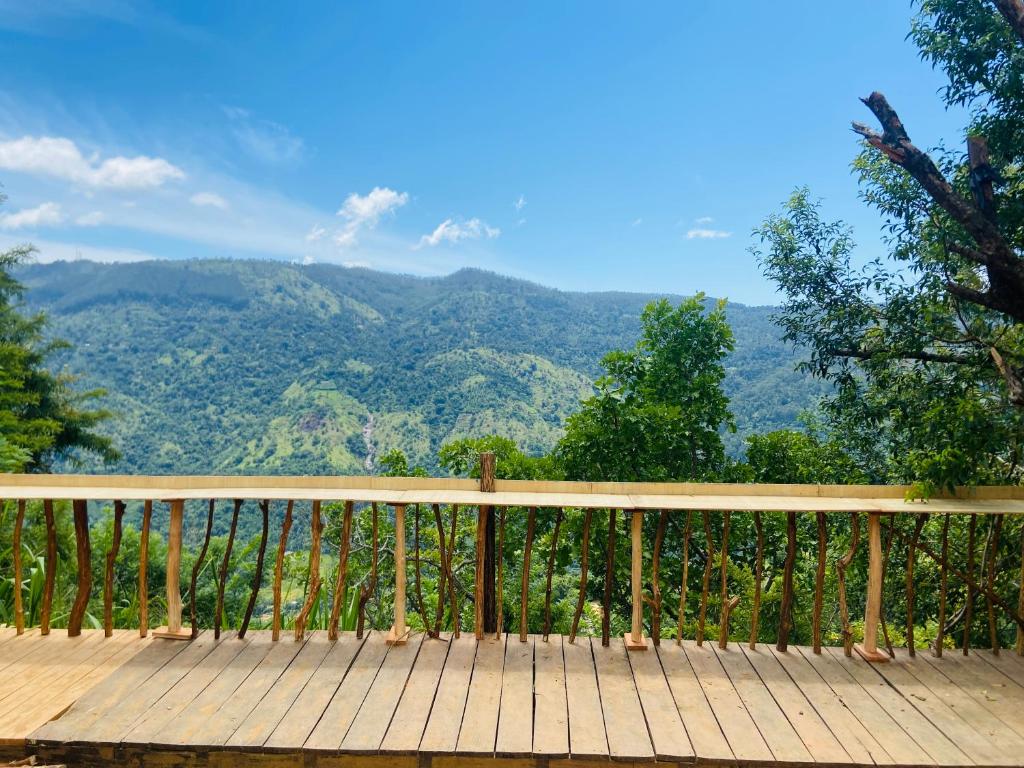 a wooden deck with a view of the mountains at The Cliff Tea Glamping in Badulla