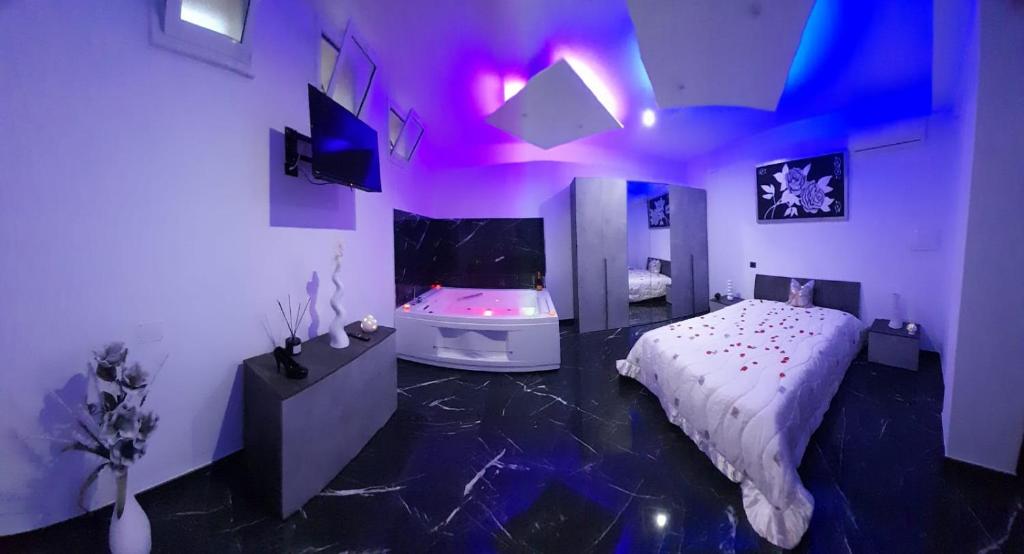una camera da letto con luci viola, un letto e una vasca di Casa Birmano a Taranto