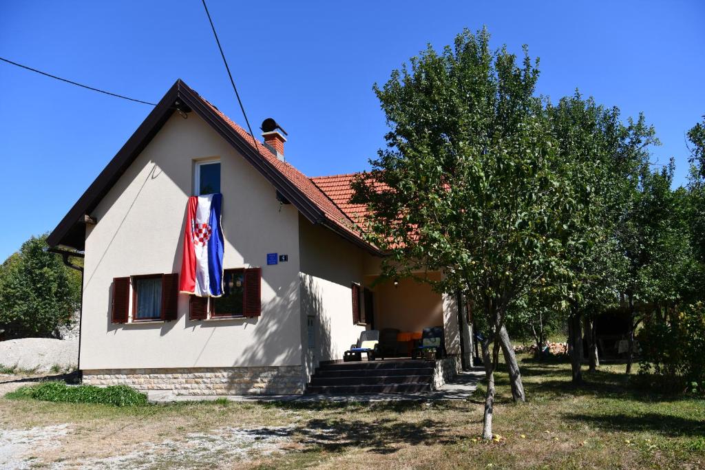 a house with a flag on the side of it at Holiday Home Matan in Saborsko