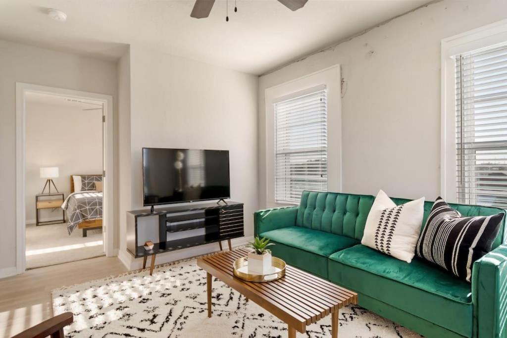 a living room with a green couch and a tv at Chic Downtown Waco Apartment in Waco