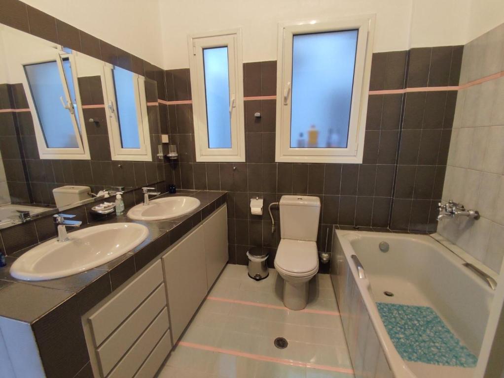 a bathroom with two sinks and a toilet and a tub at Dr. J. Spon Apartment in Nafpaktos