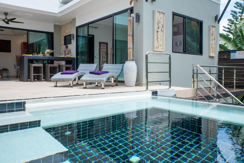 a swimming pool with two chairs and a house at Villa Anne in Lamai