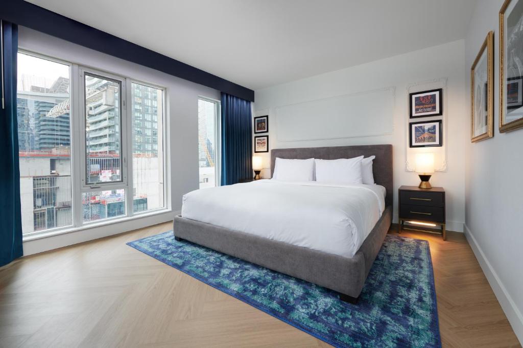a bedroom with a large bed and a large window at Pantages Hotel Toronto Centre in Toronto