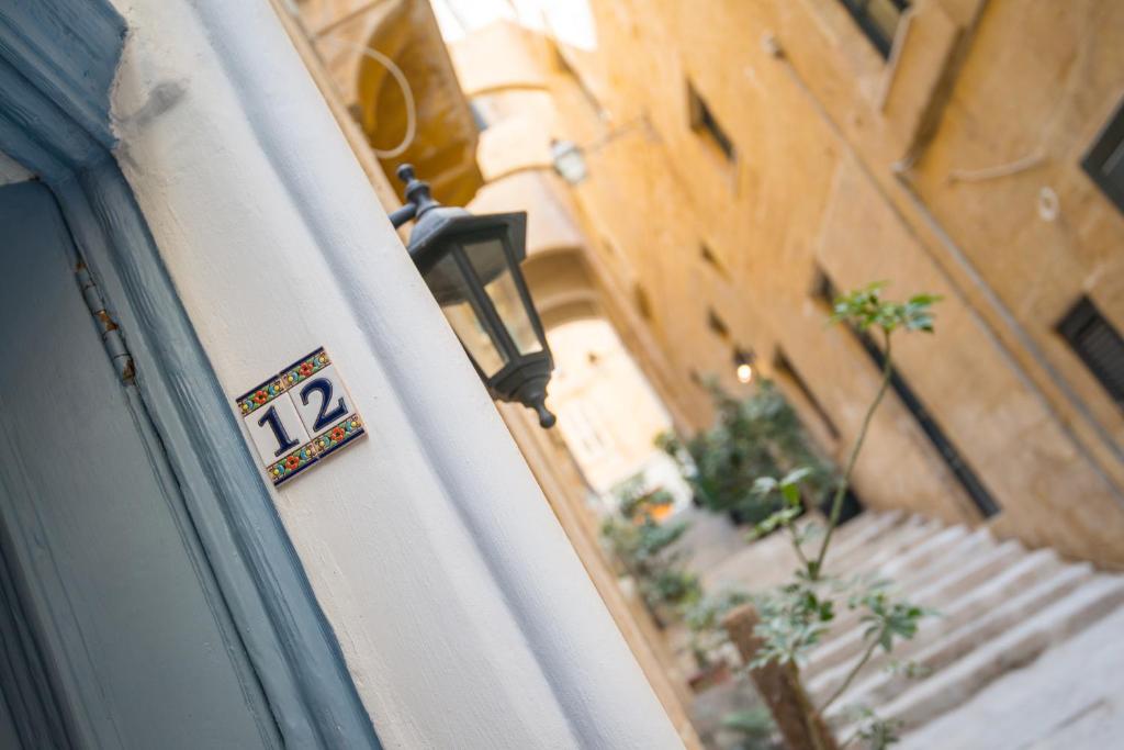 une porte avec un panneau sur le côté du bâtiment dans l'établissement Valletta most central studio apartment 16th-Century building, à La Valette