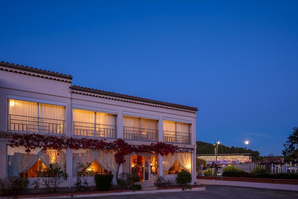 a large white building with flowers on it at night at HÖTEL LE CASTELLAN in Istres