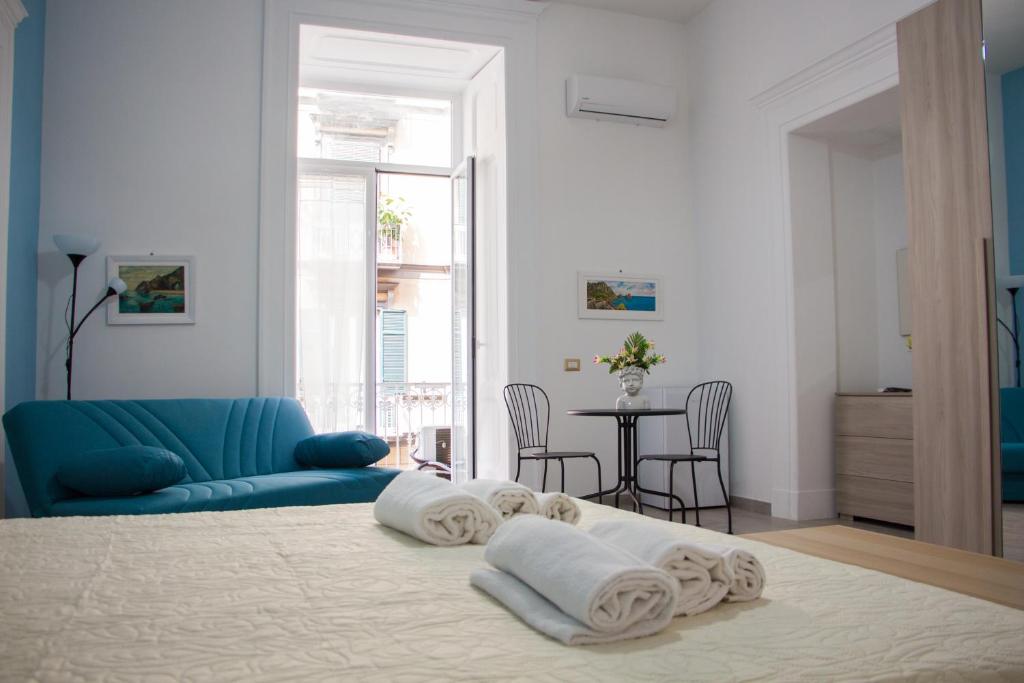 1 dormitorio con sofá azul y 1 cama con toallas en Donna Laura Suite, en Nápoles