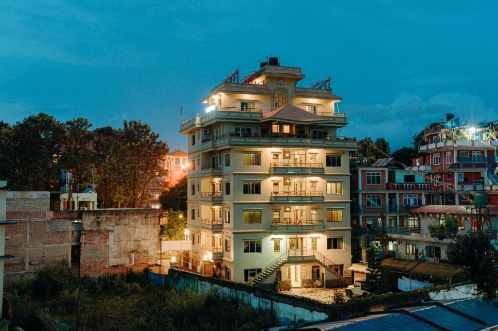 un edificio blanco alto con luces encendidas en Tise Hotel en Katmandú