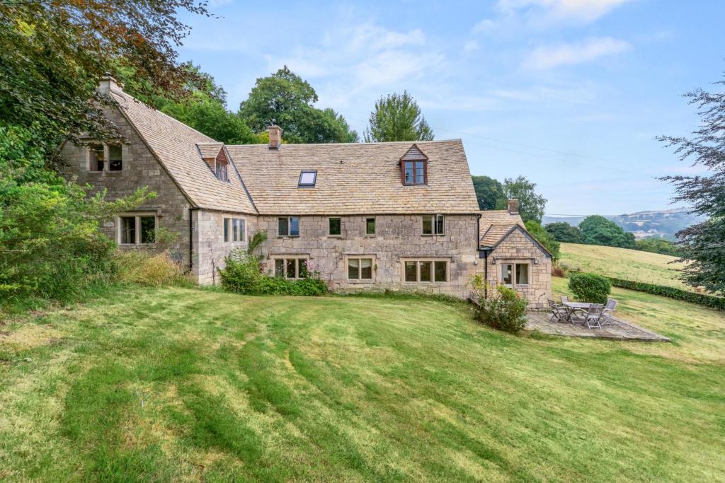 an old stone house with a grassy yard at Locks Cottage in Cheltenham