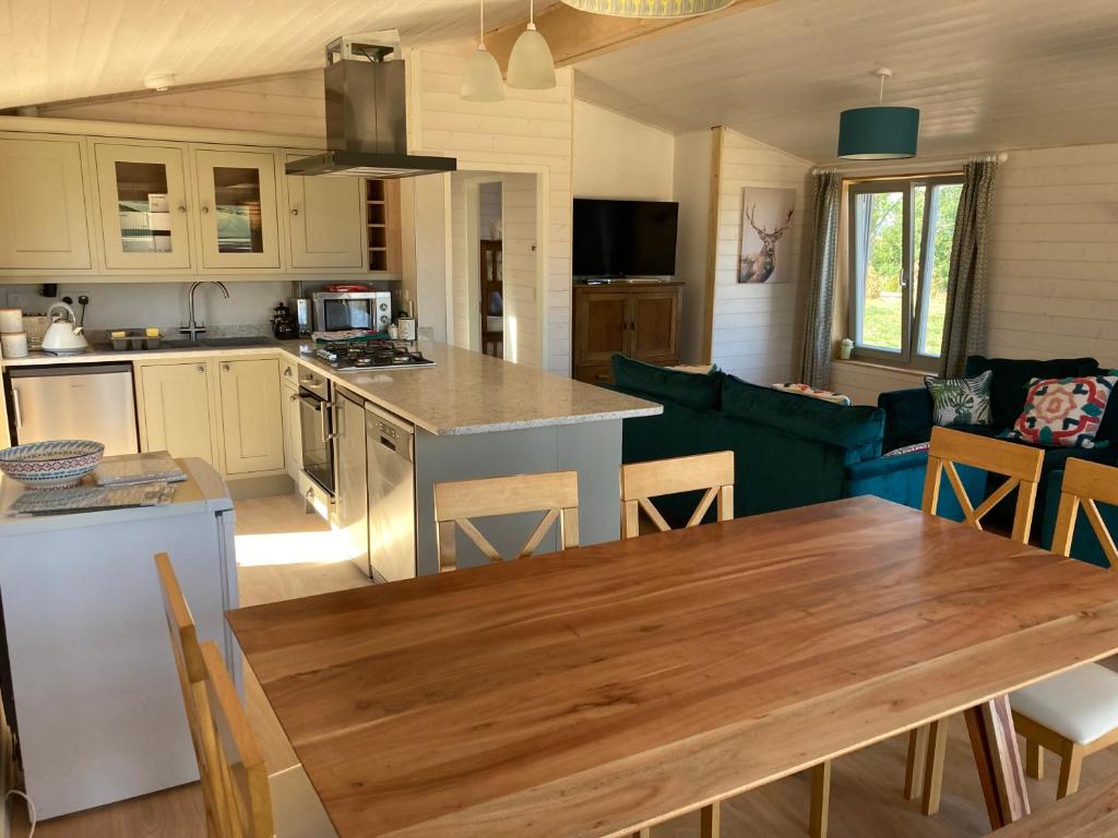 eine offene Küche und ein Wohnzimmer mit einem Holztisch in der Unterkunft Stag Lodge School House Farm in Leighton