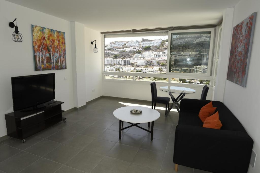 een woonkamer met een bank, een tv en een tafel bij Apto. Dulia in Puerto Rico de Gran Canaria