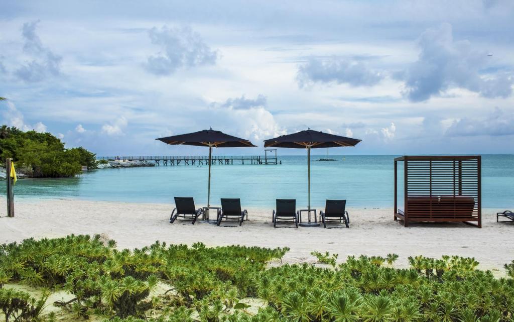 two umbrellas sit on a beach near the ocean at Nizuc Resort & Spa in Cancún