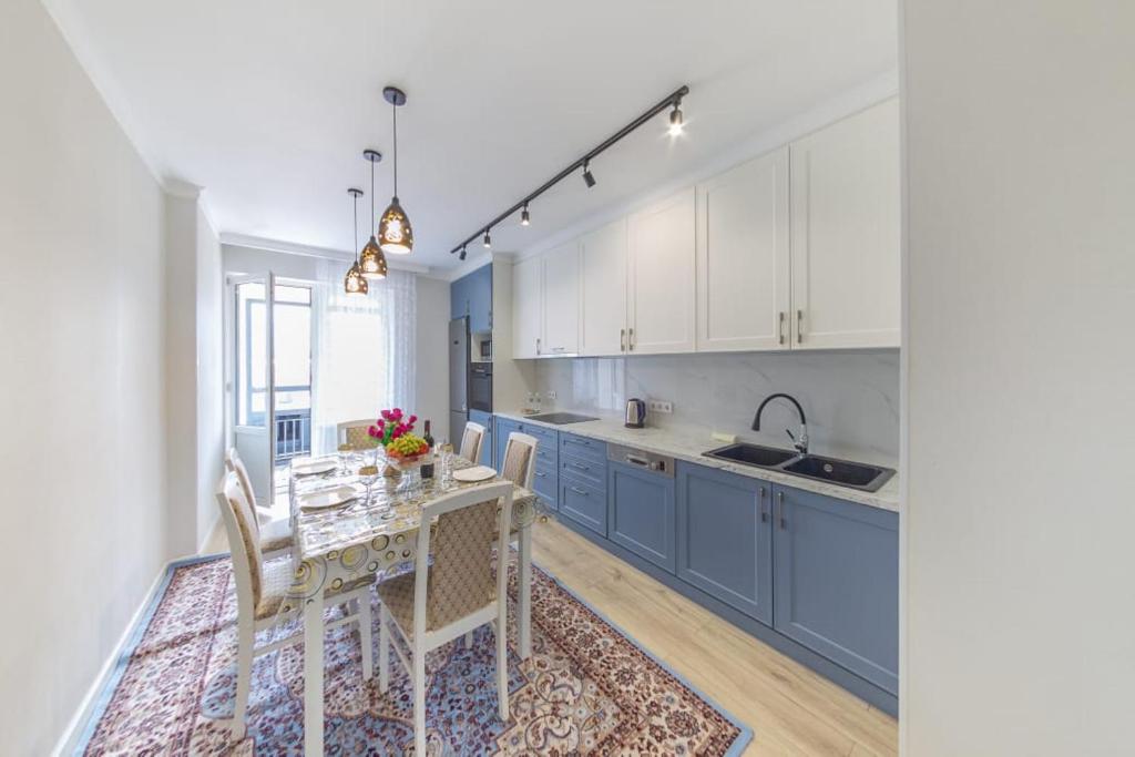 une cuisine avec des placards bleus et une table avec des chaises dans l'établissement Квартира посуточно Бизнес класса в ЖК Асыл Тобе, à Almaty