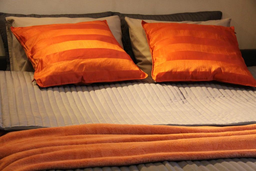 ein Bett mit orangefarbener und weißer Bettwäsche und zwei Kissen in der Unterkunft Apartment Lisinski S in Zagreb