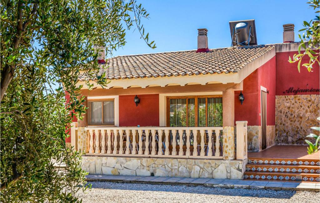 uma casa vermelha com uma cerca de madeira em frente em Cozy Home In Caravaca De La Cruz With Kitchen em Caravaca de la Cruz