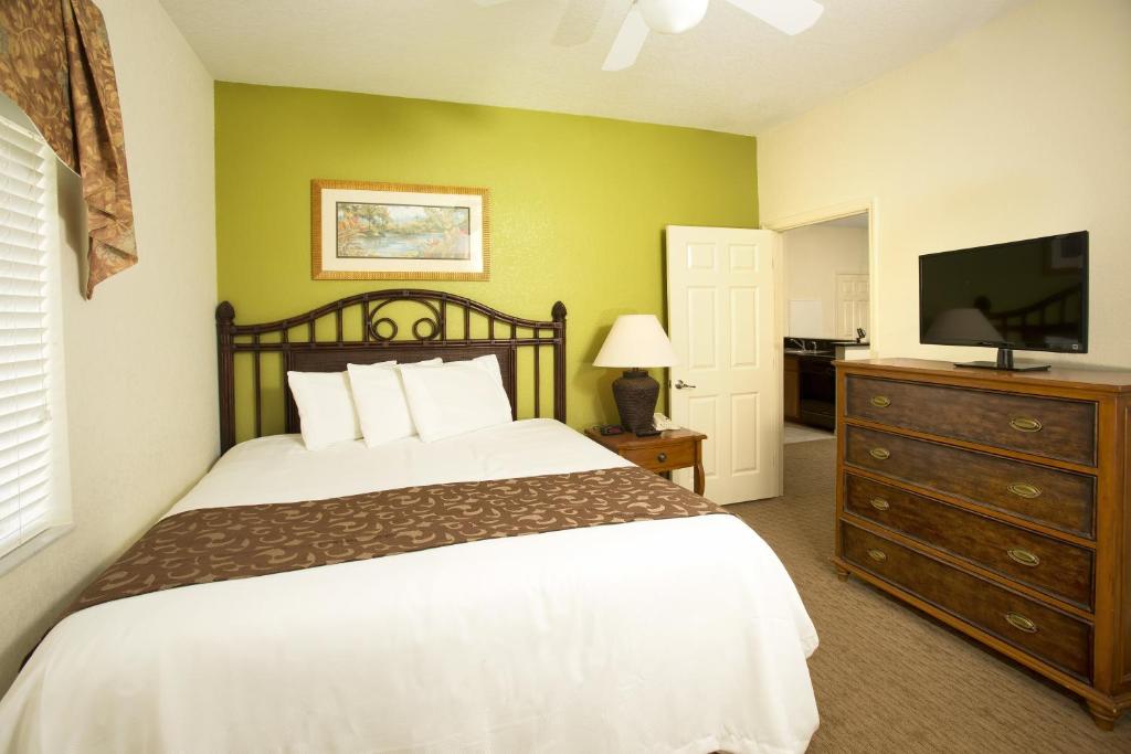 a bedroom with a bed and a flat screen tv at Lake Buena Vista Resort Village and Spa, Near Disney in Orlando