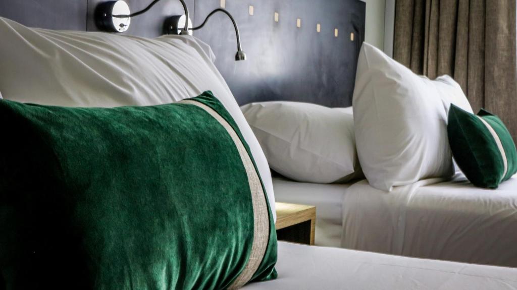 a room with a bed with pillows and a couch at Ecohotel Talca in Talca