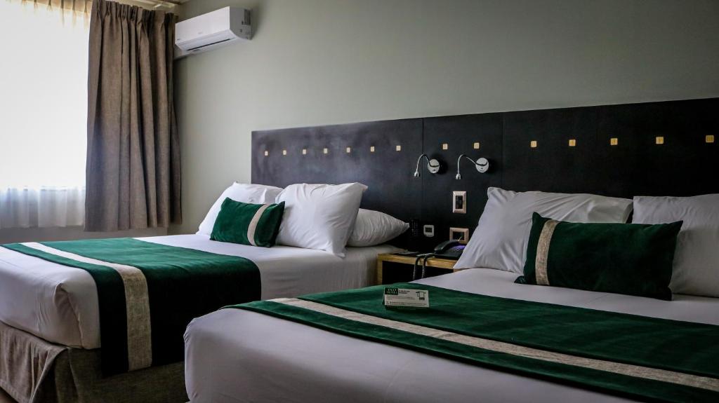 a hotel room with two beds with green and white at Ecohotel Talca in Talca