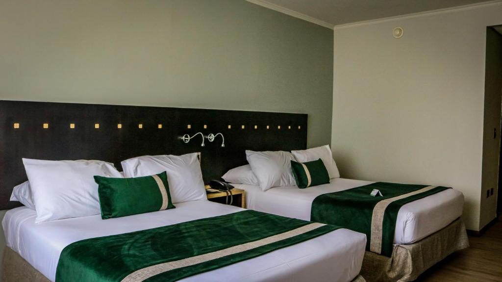 two beds in a hotel room with green and white at Ecohotel Talca in Talca