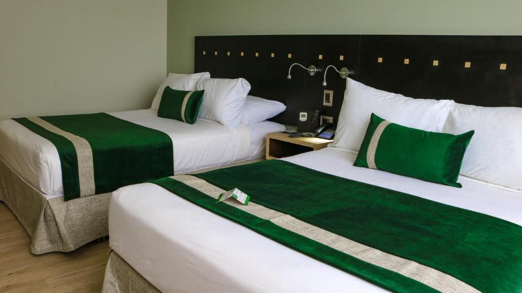 two beds in a hotel room with green and white at Ecohotel Talca in Talca