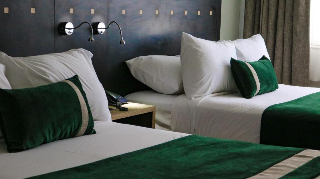 a hotel room with two beds and a couch at Ecohotel Talca in Talca