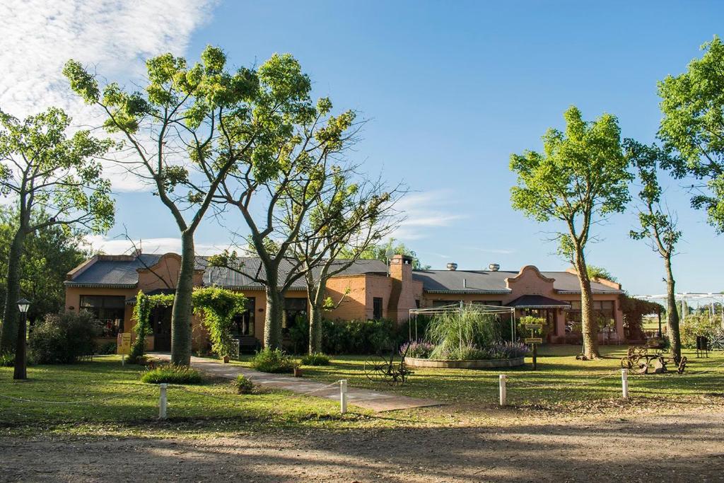 a building with trees in front of a park at Pampas del Sur Hotel y Spa de campo in Cañuelas