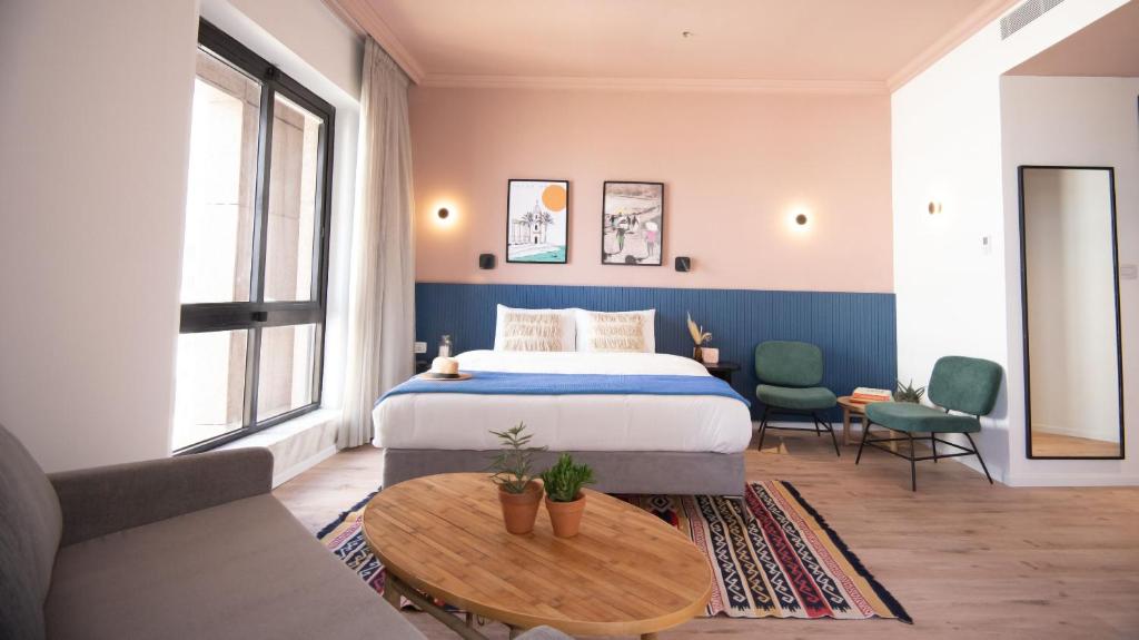 een slaapkamer met een bed, een tafel en een bank bij Selina Tel Aviv Beach in Tel Aviv