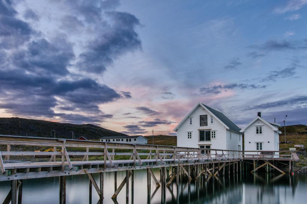 a white house on a dock next to the water at Lovisenborg Brygge in Kongsfjord