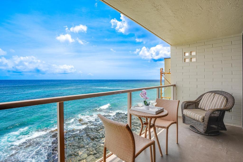 a balcony with chairs and a table and the ocean at Kuhio Shores 410 in Koloa