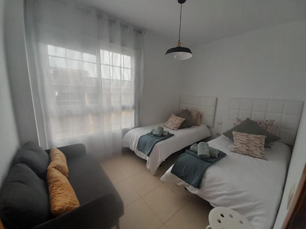 un soggiorno con 2 letti e un divano di Arode Apartamento a Los Abrigos
