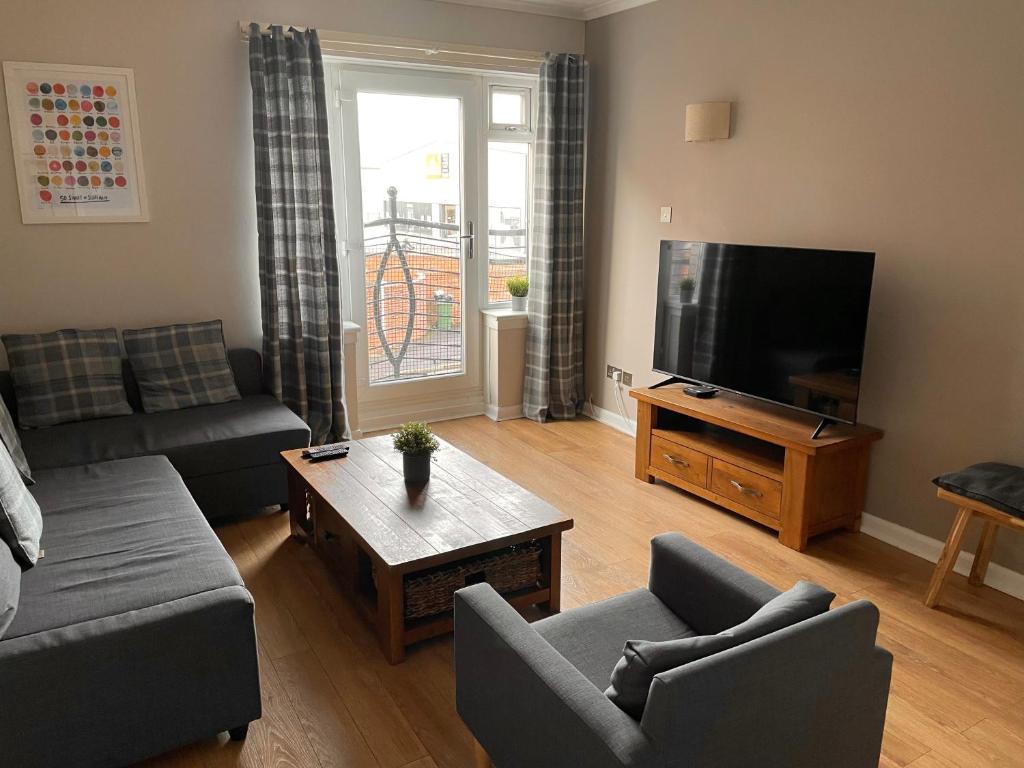 a living room with a couch and a flat screen tv at The Abercromby Townhouse - Close to Merchant City in Glasgow