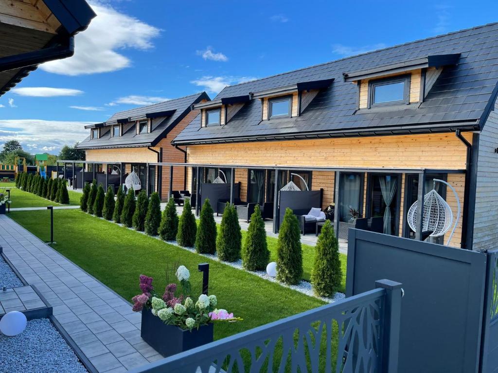 une maison avec un jardin en face dans l'établissement Luksusowe Domki Kalimera, à Jantar