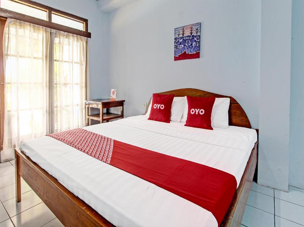 a bedroom with a large bed with red pillows at Capital O 91644 Loka Hause in Salatiga
