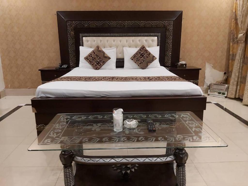 a bedroom with a large bed with a table in it at Hotel Visit Inn One in Lahore