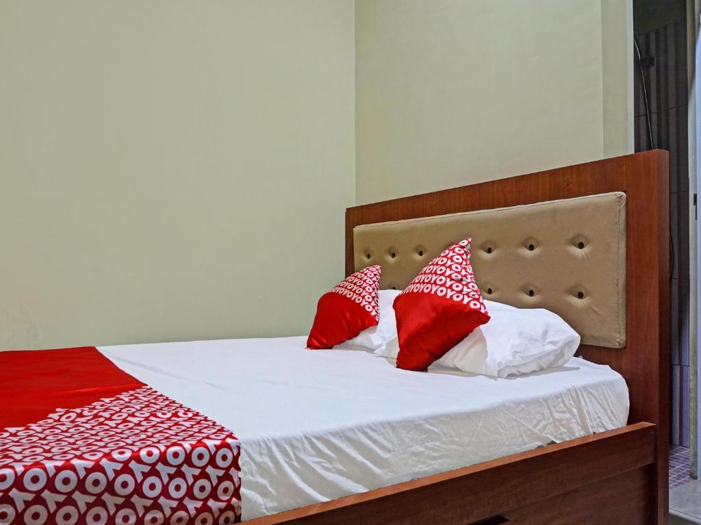 a bed with red and white pillows on it at OYO 91649 Orange Homestay Makassar in Makassar