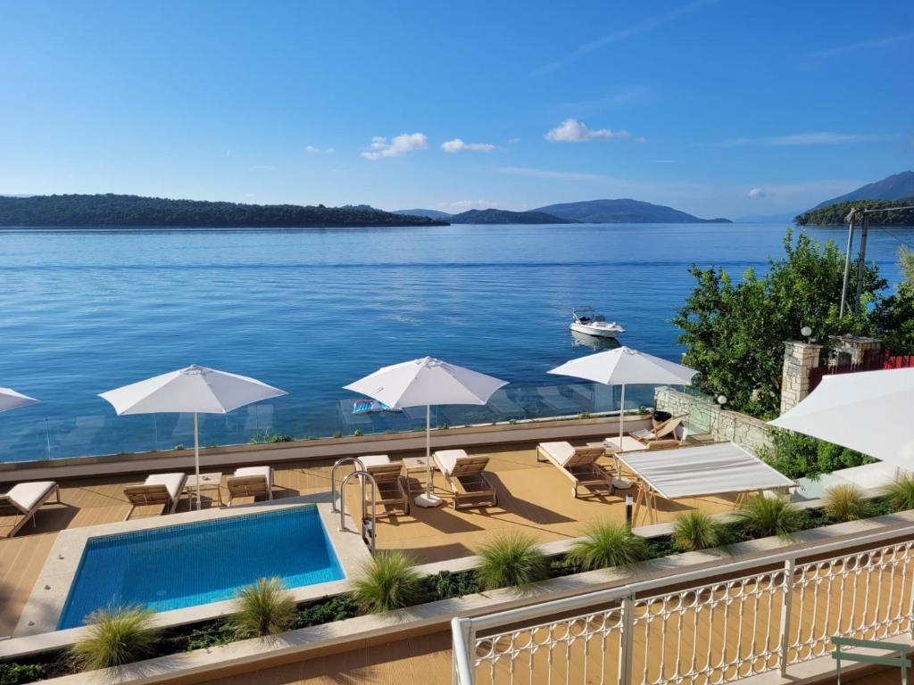 a swimming pool with umbrellas and chairs and the water at Greek Beach House A3 Lefkada in Nydri