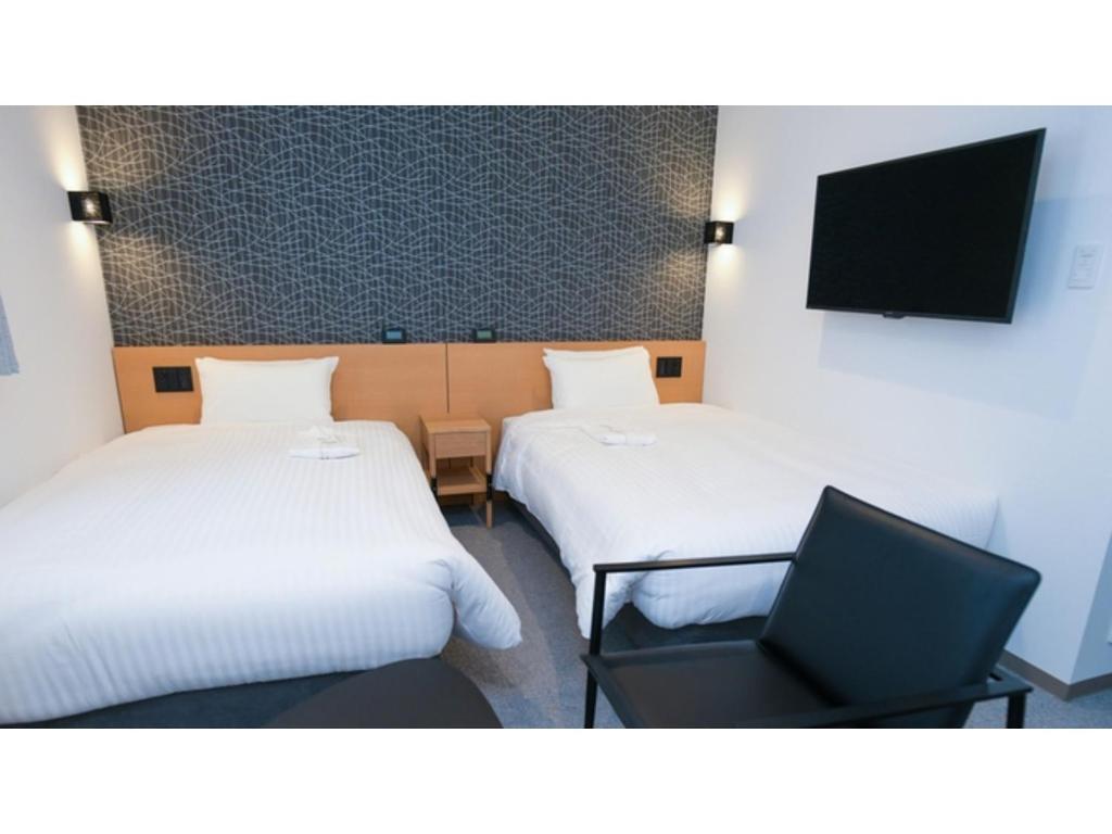 Pokój z 2 łóżkami, krzesłem i telewizorem w obiekcie ＹＯＵ ＳＴＹＬＥ ＨＯＴＥＬ ＨＡＫＡＴＡ - Vacation STAY 16033v w mieście Fukuoka