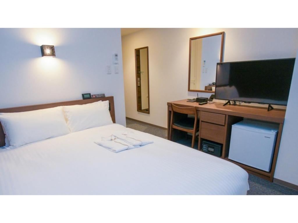 Schlafzimmer mit einem Bett und einem Schreibtisch mit einem TV in der Unterkunft ＹＯＵ ＳＴＹＬＥ ＨＯＴＥＬ ＨＡＫＡＴＡ - Vacation STAY 16027v in Fukuoka