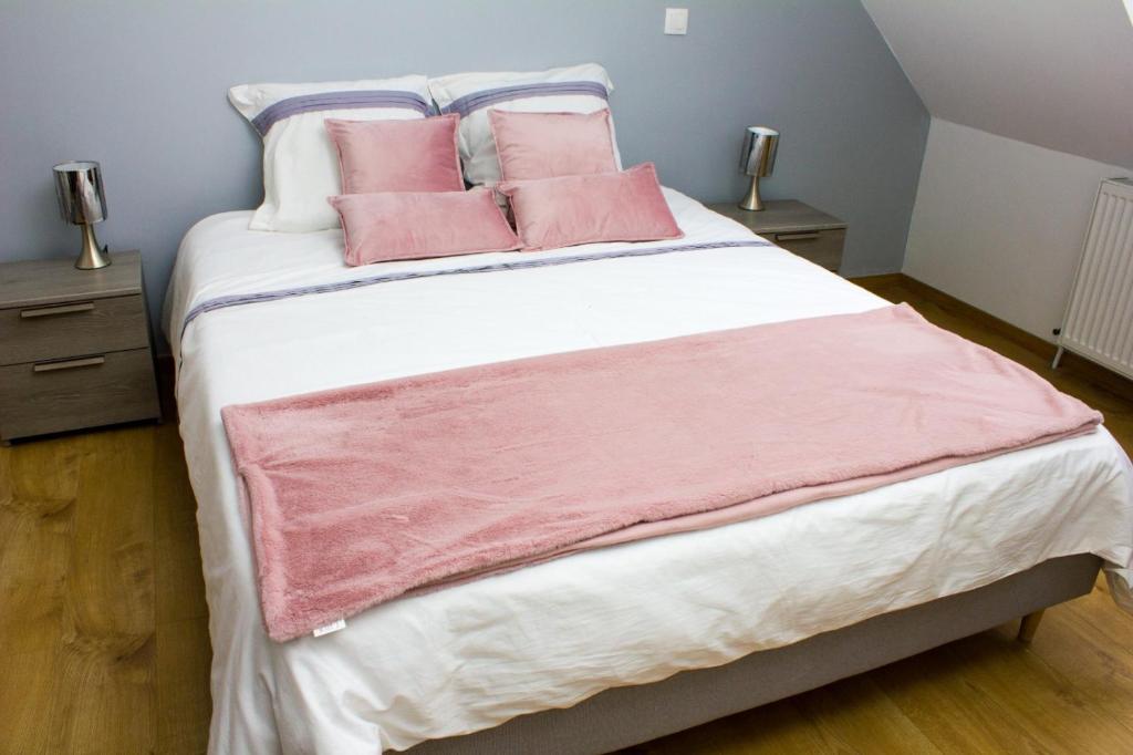 um quarto com uma cama grande e almofadas cor-de-rosa em F2 Duplex chez l'aventurière près Disneyland em Roissy-en-Brie